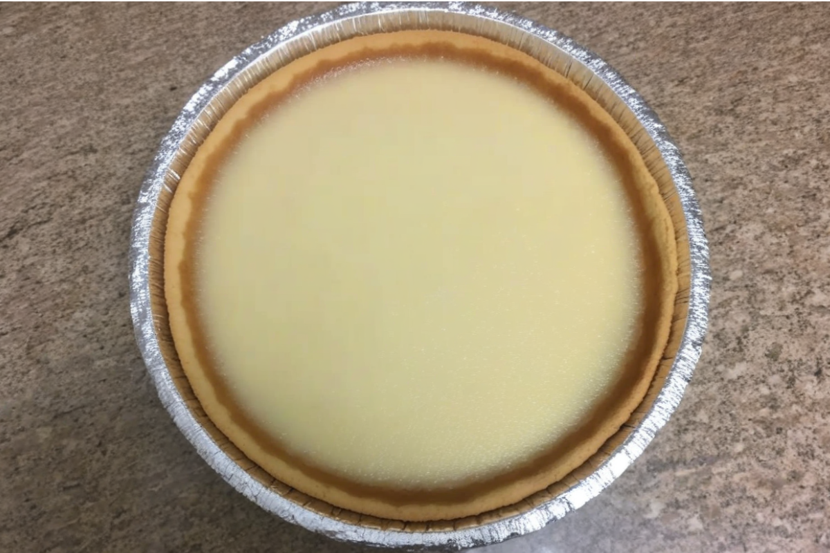 A beautifully baked Philadelphia cheesecake with a golden crust and creamy center, garnished with fresh berries.